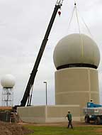 A crane lifts the radome into position atop the new phased array radar building.