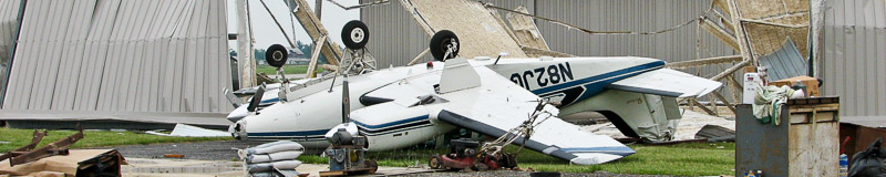small private plane turned upside down in front of a demolished building