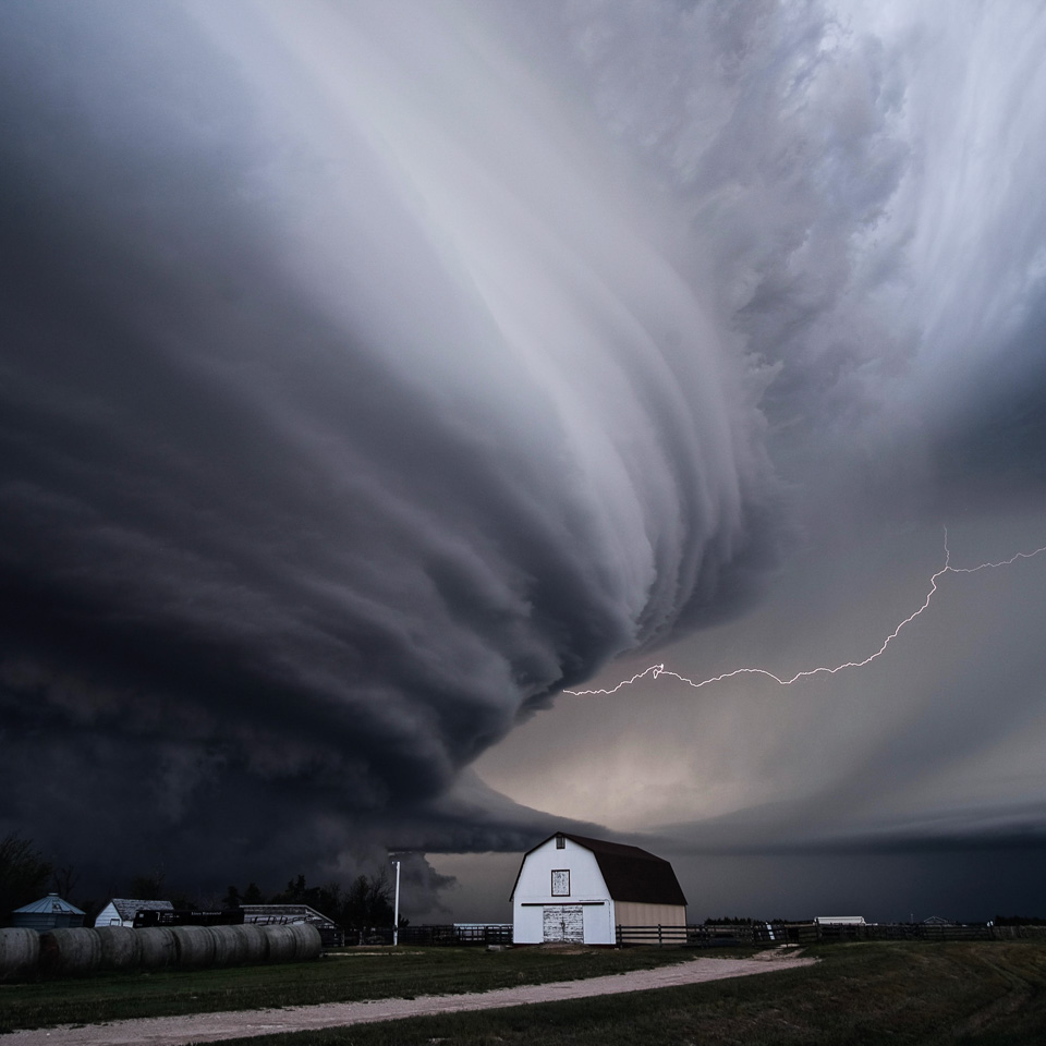 mesocyclone thunderstorm cloud over a barn, with lightning extending from one side