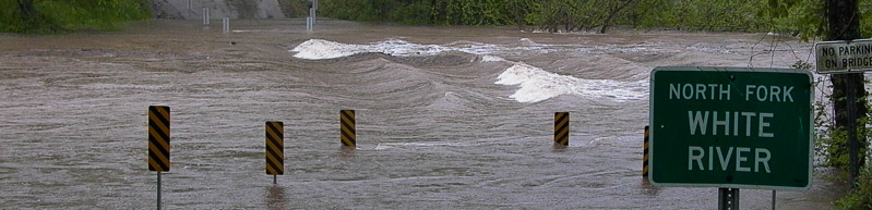 road covered by rushing flood waters