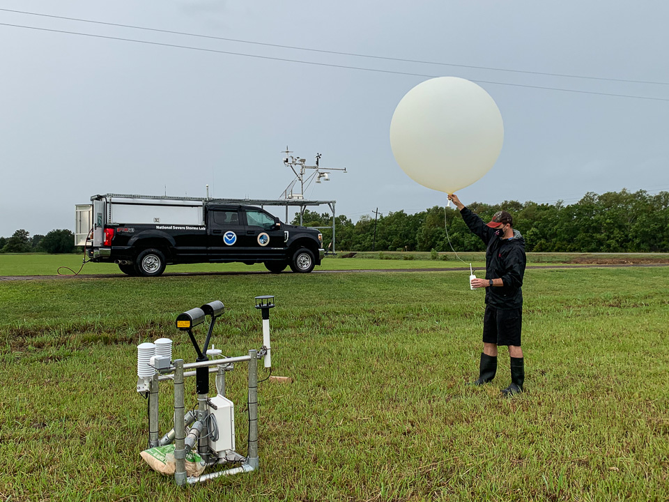 Researcher wearing medical mask holding weather balloon in a field