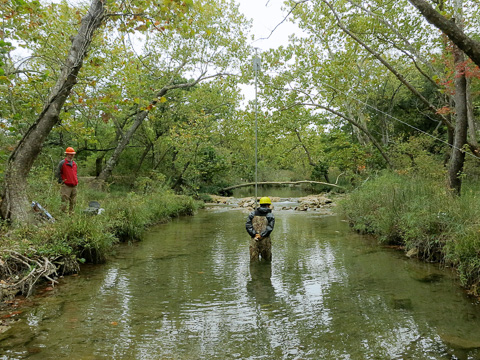 researcheers setting sensors over a creek'