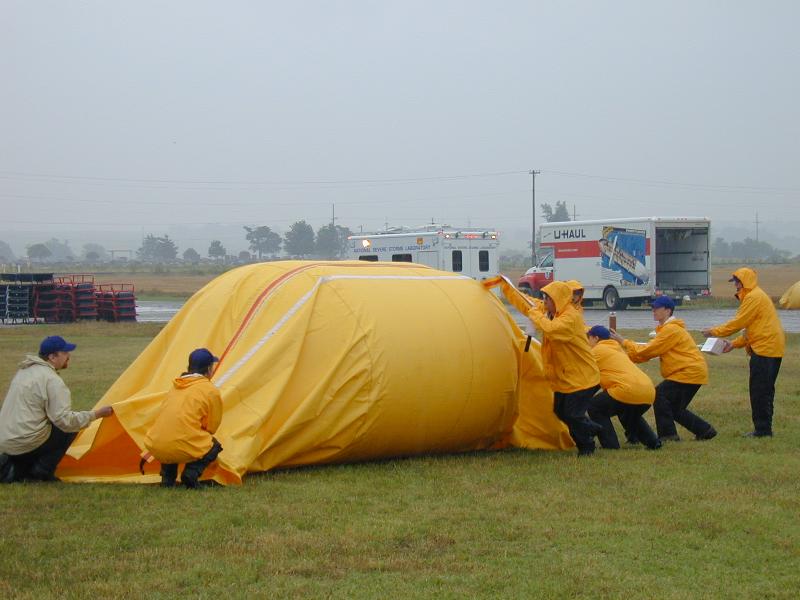Students help scientists launch an instrumented balloon into a morning mesoscale convective system during TELEX 2003. The yellow tube is the launch tube containing the balloon, and crew members on the right are holding instruments in the balloon train.